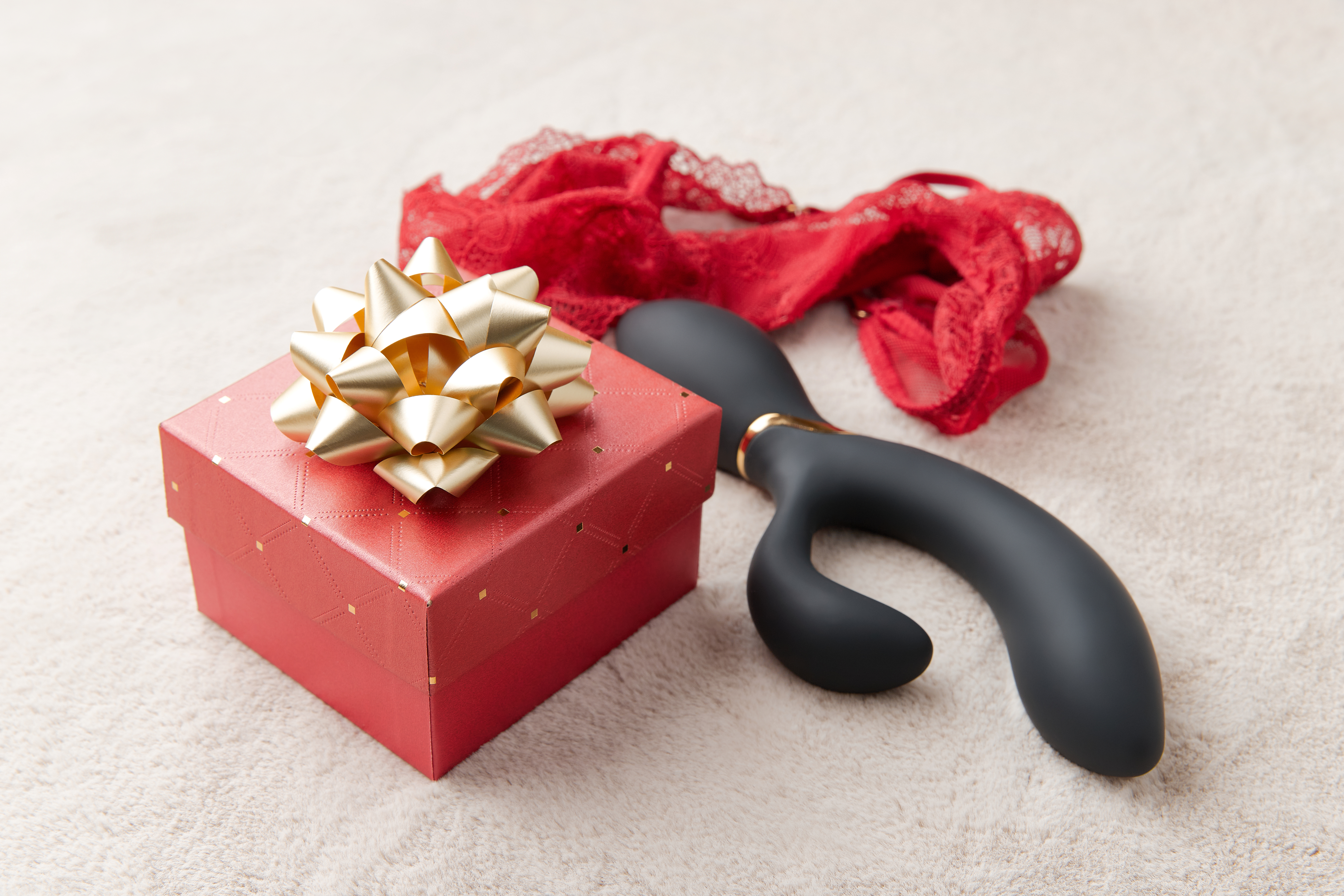 black-vibrator-red-lingerie-red-gift-box-with-golden-bow-white-fur-background.jpg